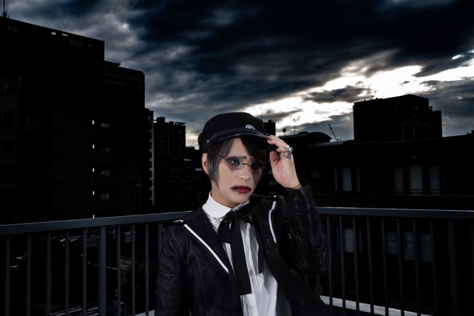 黒い帽子と眼鏡、黒い衣装を身に着けたgaizaoのアーティスト写真。横長に変形して表示。